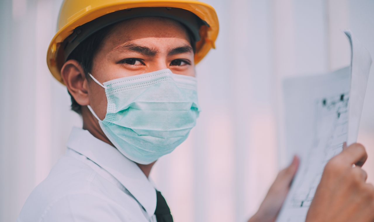 Ingenieur en casque de chantier examinant des plans sur un chantier de construction, formation anglais BTP Cabinet Action