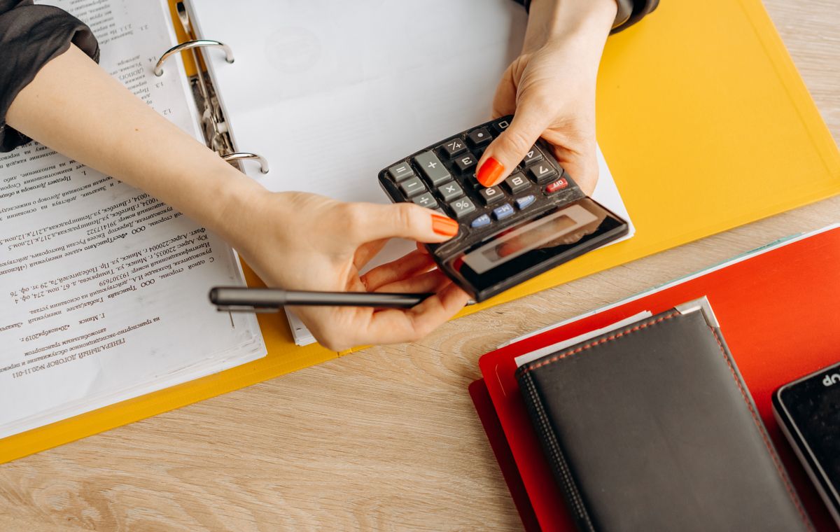 Comptable analysant des documents financiers avec une calculatrice au bureau, formation anglais comptable Cabinet Action