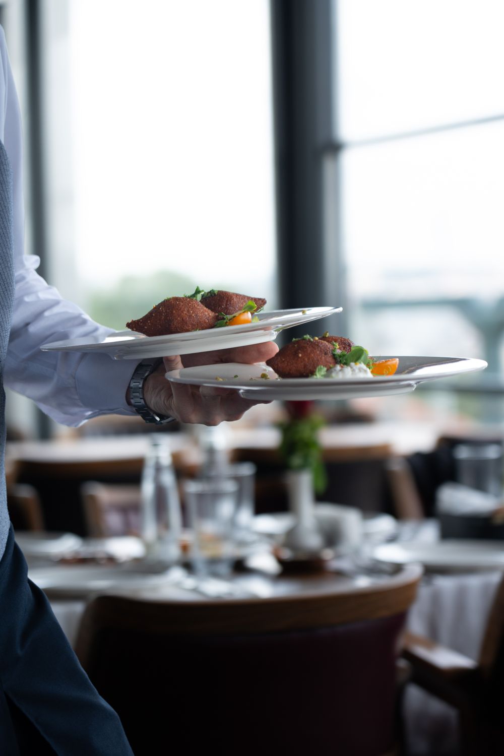 Serveur en salle apportant des plats dans un restaurant gastronomique, formation anglais restauration Cabinet Action