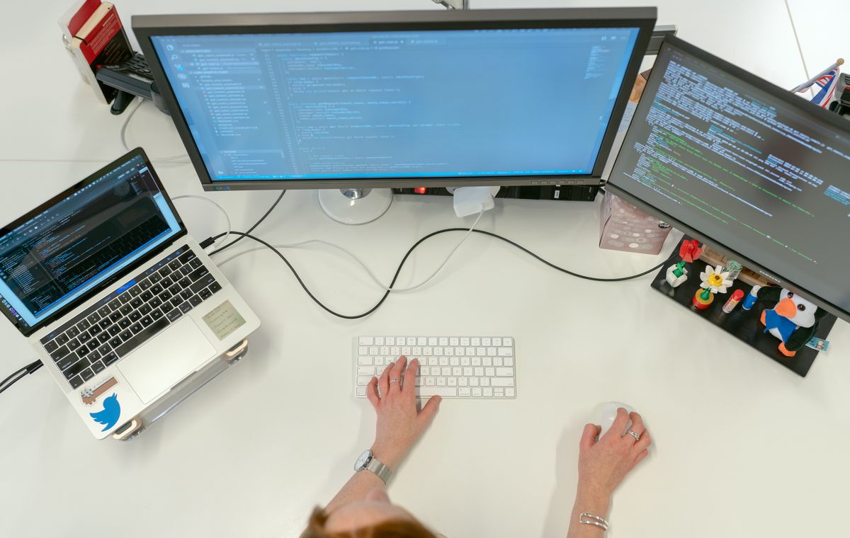 Développeuse codant sur plusieurs écrans dans un bureau, formation anglais informatique Cabinet Action